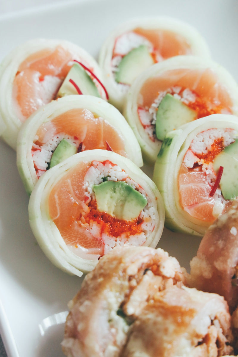 a white plate topped with rolls covered in cucumbers