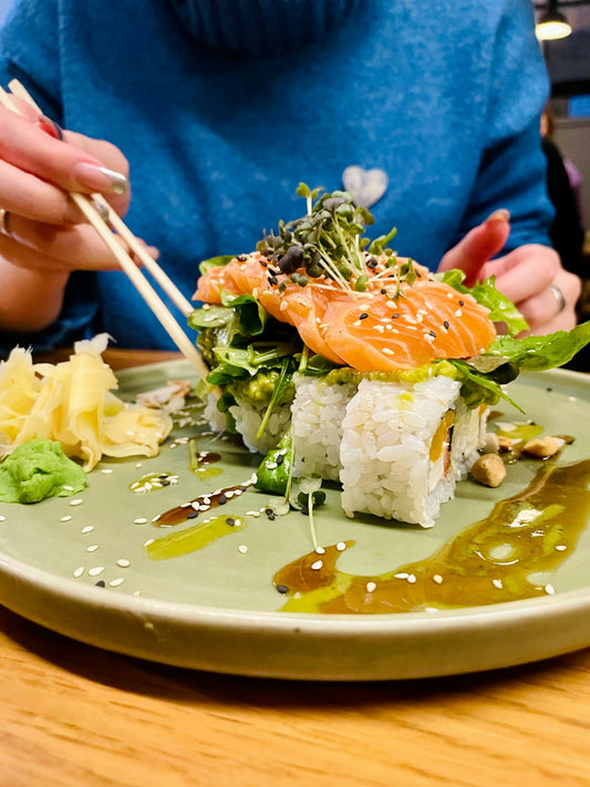 a woman eating sushi with chopsticks on a plate