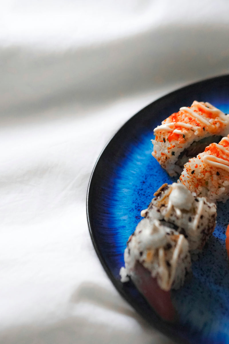 A blue plate topped with sushi and vegetables