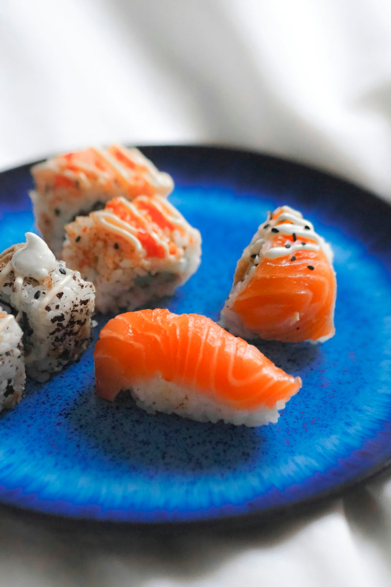 A blue plate topped with sushi on top of a table