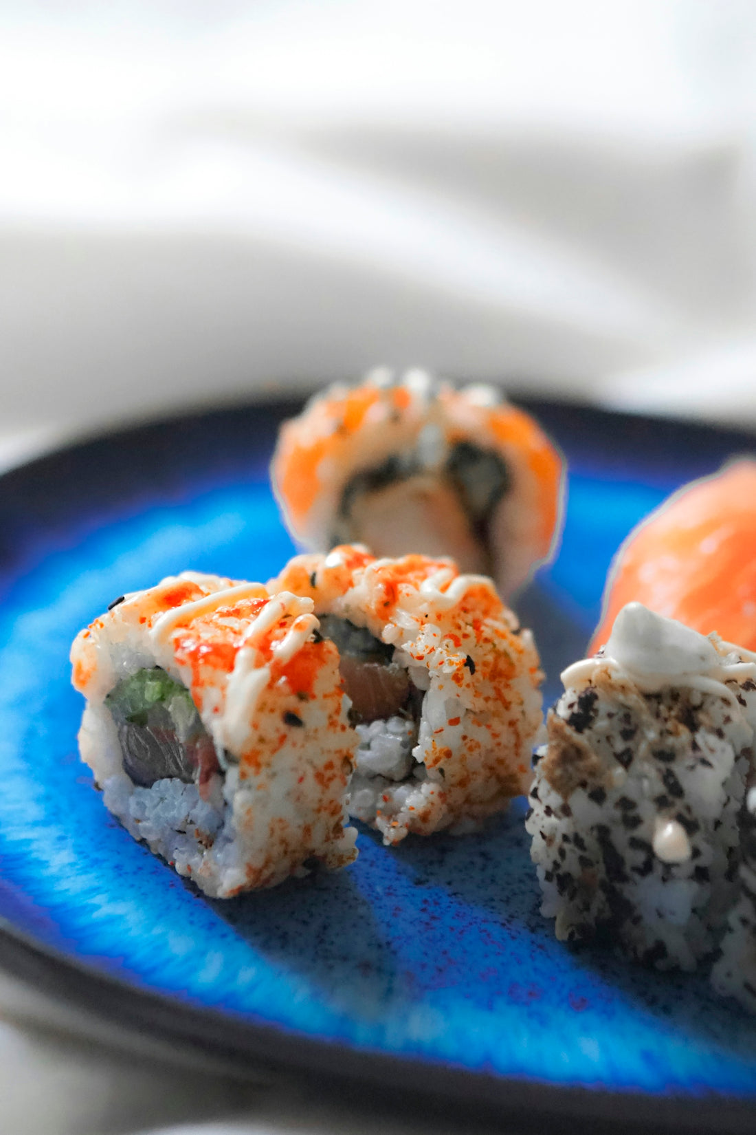 A blue plate topped with sushi covered in sauce